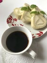 On the table stand a plate with a ready sliced roll, decorated with lemon bald leaves. A cup of coffee.