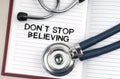 On the table is a stethoscope, a pen and a notebook in which it is written - Dont Stop Believing