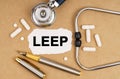 On the table is a stethoscope, pills, a pen and paper with the inscription - LEEP Royalty Free Stock Photo