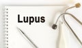 On the table are a stethoscope, a thermometer, a pen and a notebook with the inscription -Lupus Royalty Free Stock Photo