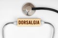 On the table is a stethoscope and a wooden plate with the inscription - DORSALGIA Royalty Free Stock Photo