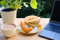 On table in summer garden there is open laptop, computer, cup of cappuccino, melon on plate, concept of downshifter`s workplace,