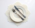 A table surface with silver cutlery set atop a lace placemat Royalty Free Stock Photo