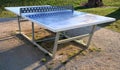 Table tennis blue table blue color net is made of metal around pebbles and sun lawn Royalty Free Stock Photo