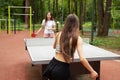 Table tennis in park, two girls playing with ping pong rackets Royalty Free Stock Photo