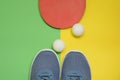 Table tennis racket, balls and sport sneakers on yellow green background Royalty Free Stock Photo