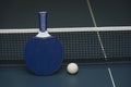 Table tennis rackets and ball and net on a blue pingpong table Royalty Free Stock Photo