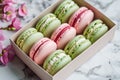 On the table there is a box with colorful pastries - macaroons and flowers. A beautifully packaged dessert is a wonderful holiday