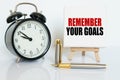 On the table there is a clock, a pen and a stand with a card on which the text is written - REMEMBER YOUR GOALS