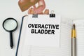 On the table there is a magnifying glass and a notepad with the inscription - Overactive bladder