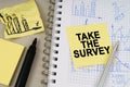 On the table there is a notepad with notes and sticky notes with the inscription - Take the Survey