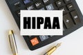 On the table there is a pen, a calculator and a business card on which the text is written HIPAA. THE HEALTH INSURANCE PORTABILITY Royalty Free Stock Photo