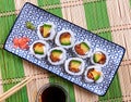 On table there is plate with set of sushi - uramaki rolls california roll with chees