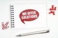 On the table there are stationery, a notebook and a red sign with the inscription - We Offer Solutions Royalty Free Stock Photo