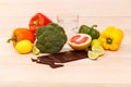 On the table is a chocolate, a glass of water and useful citrus fruits and vegetables. Healthy diet. Side view. Inside. Royalty Free Stock Photo