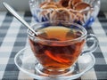 On the table there is a transparent glass Cup with tea on a glass saucer and a glass vase with bagels