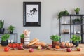 Table with tomatoes, bread, apples and herbs in a rustical dining room interior