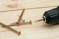 Electric screwdriver on a wooden table. Side view of the black metallic screws, electric screwdriwer on the wodden boards