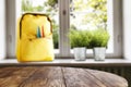 Table top with empty space for products or decoration, yellow schoolbag, red mug, blurred spring outside the window background. Royalty Free Stock Photo