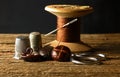 OLD VINTAGE WOODEN REEL WITH BROWN THREAD, SCISSORS, LEATHER BUTTONS, THIMBLES AND A NEEDLE Royalty Free Stock Photo