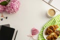 Table top of work space frame with cup of coffee, croissants, pink hydrangea and notebooks Royalty Free Stock Photo