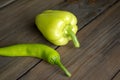 On the table are two types of pepper - green chili and green bell. Sweet and hot peppers on a wooden table. Royalty Free Stock Photo