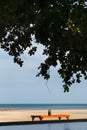 table under shade and tree on the beach with ocean and pool in a scene on evening sunlight Royalty Free Stock Photo