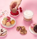 Table with various cookies, donuts, cakes, coffee cups on pink background Royalty Free Stock Photo