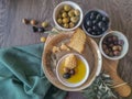 Table view consisting of several bowls with different types of olives, plate with cornbread and extra virgin olive oil, dark wood