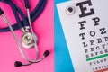 Table for visual acuity test Snellen chart and medical stethoscope is in two colors background: blue and pink. Concept of eye di Royalty Free Stock Photo