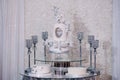 Table with a wedding cake, candles and flowers. Photo-wall, wedding decoration space or place from white and silver Royalty Free Stock Photo