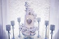 Table with a wedding cake, candles and flowers. Photo-wall, wedding decoration space or place from white and silver Royalty Free Stock Photo