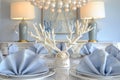 table with a white coral chandelier above, bluewhite porcelain, and pearl napkin rings