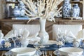 table with a white coral chandelier above, bluewhite porcelain, and pearl napkin rings