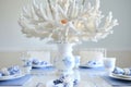 table with a white coral chandelier above, bluewhite porcelain, and pearl napkin rings