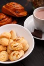 On the table in a plate are several bagels with jam. Next to the plate is cocoa and buns.