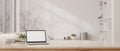 A table with a white-screen laptop mockup over a blurred white living room in the background Royalty Free Stock Photo