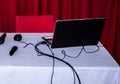 table with white tablecloth with an open laptop resting on top, with background and red chair Royalty Free Stock Photo