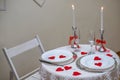 Table with white tablecloth. Romantic candlelight dinner. White fireplace decorated with red hearts for Valentine's Royalty Free Stock Photo
