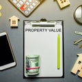 Table with wooden houses, calculator, coins, magnifying glass with the word Property value. The contract for real estate appraisal Royalty Free Stock Photo