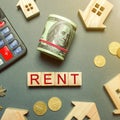 Table with wooden houses, calculator, coins, magnifying glass with the word Rent. The concept of rental housing. Rent an apartment