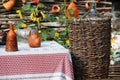 the table in the yard is covered with a white tablecloth with a red stripe, pottery and various jugs of clay, a large wicker Royalty Free Stock Photo