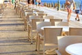 The tables and chairs of the beach cafe are located along the promenade amid strolling people and the blue sea Royalty Free Stock Photo