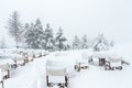 Restaurant tables and chairs under a snowstorm