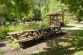 Wooden tables and benches suitable for lunch or snack in the woods next to a green meadow in the camp. Royalty Free Stock Photo