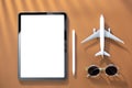 Tablet, airplane miniature and sunglasses, top view, copy space.