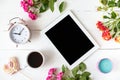 Tablet, alarm clock, cup of coffee, roses, candles on the table. Women`s things Fashion womens desk