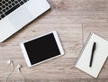 Tablet with blank black screen, Laptop computer, earphones, notebook on wooden background Royalty Free Stock Photo