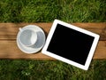 Tablet and blank coffee cup on green grass Royalty Free Stock Photo