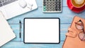 Tablet with blank screen, laptop computer, calculator, notebook, eyeglass, pen and cup of coffee on wooden desk. Royalty Free Stock Photo